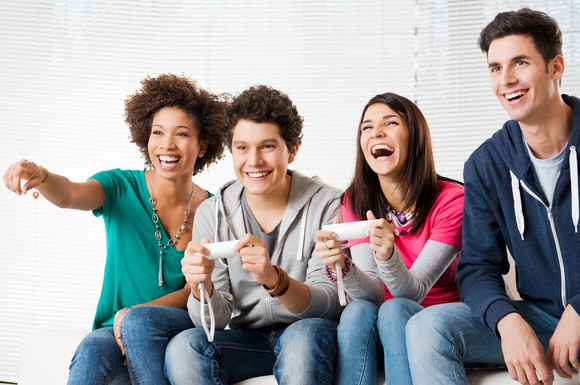A group of friends huddled on a couch playing video games.