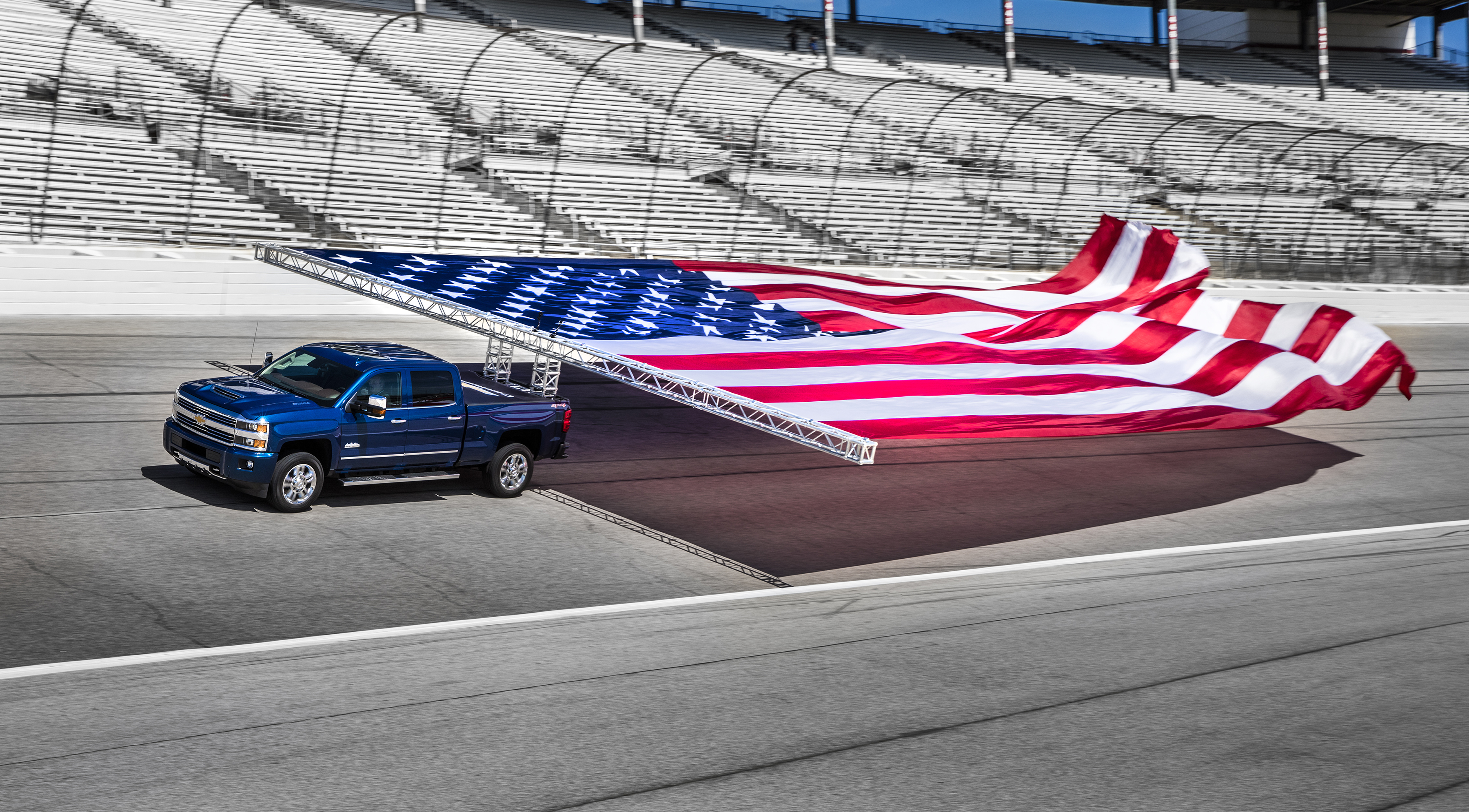GM's Silverado towing a huge American flag down a race track.