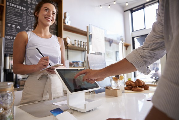 Customer making a payment on a tablet at coffee shop.
