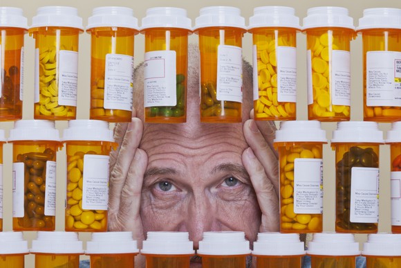 A man staring through a pile of prescription medicine bottles.