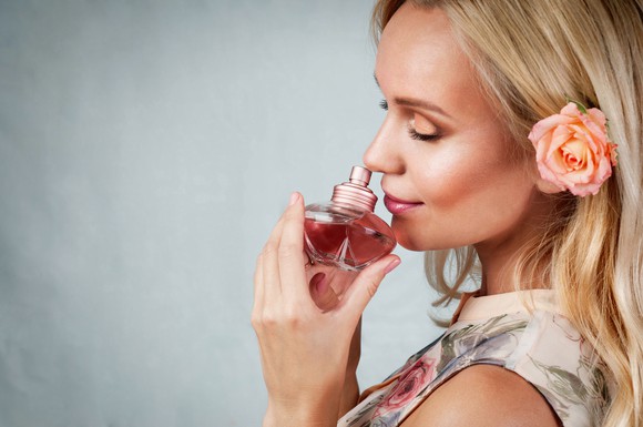 A woman smells a bottle of perfume.