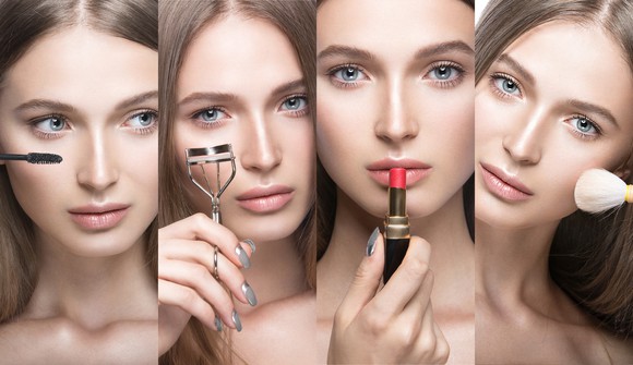 A young woman applies makeup to her face.