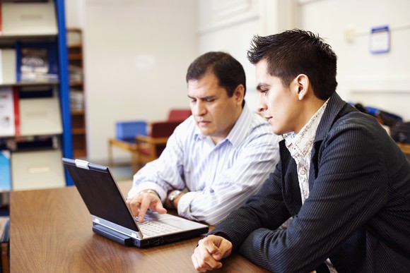 Two adults studying at a computer.