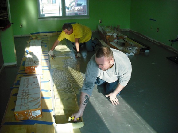 Two Lumber Liquidators installers preparing a floor for laminate flooring.