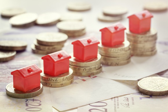 Little plastic houses on ascending stacks of coins.