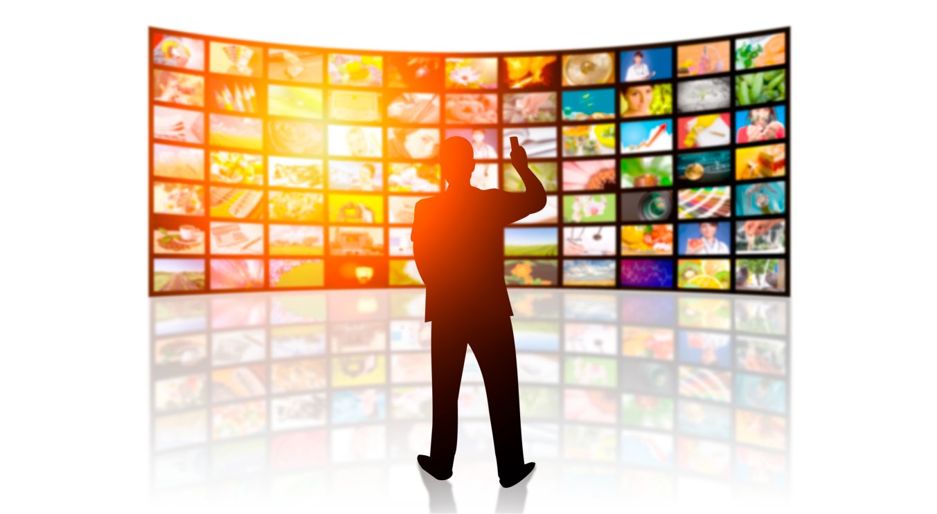 A man stands in front of dozens of LCD screens.