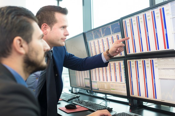 Traders looking at stock quotes on a monitor.