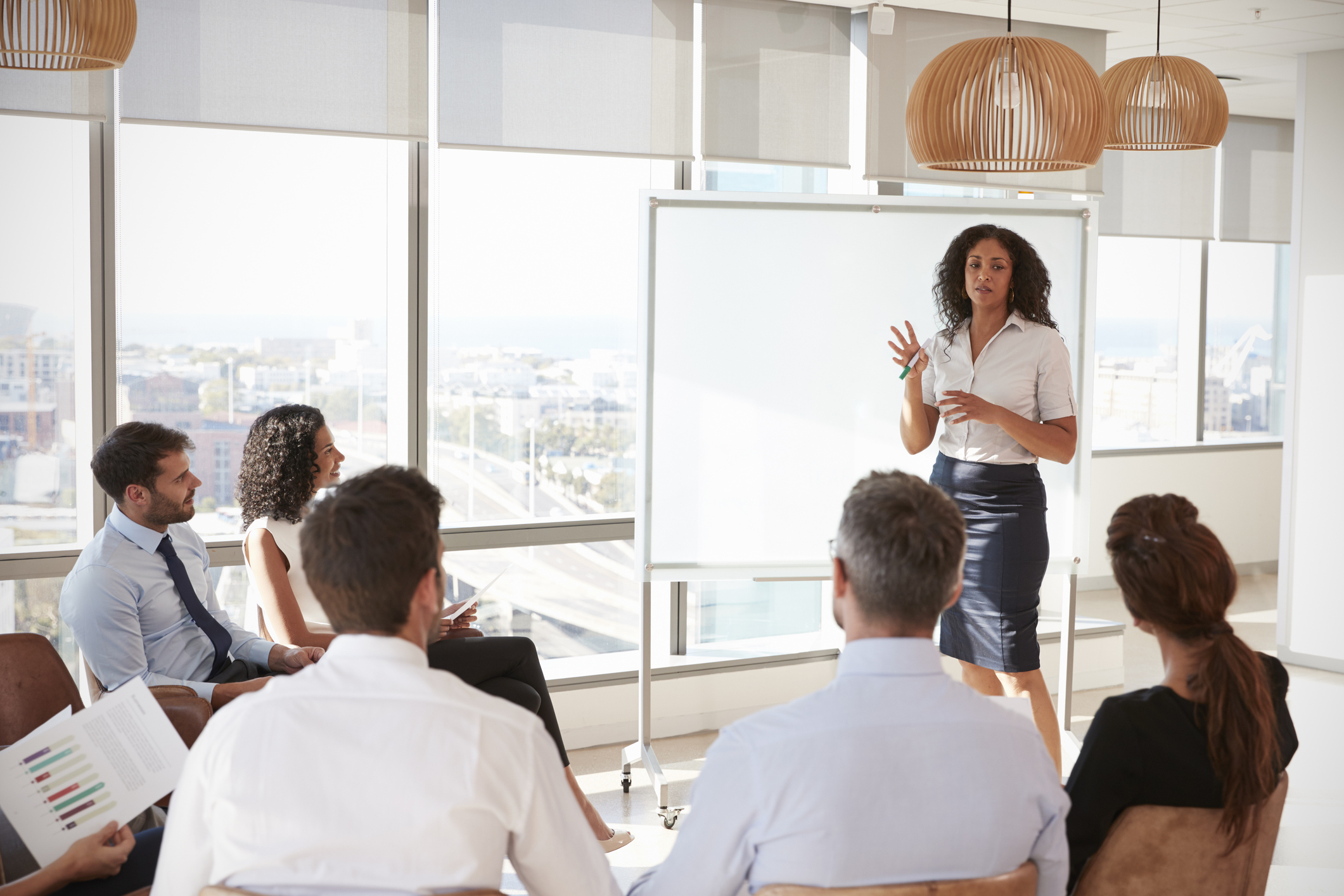 A consultant stands before a whiteboard, delivering a presentation.