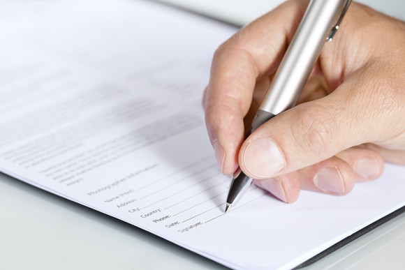Close-up of hand signing document.