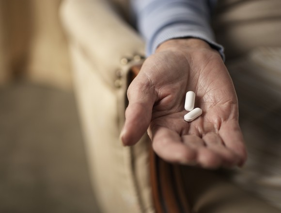 Hand holding 2 pills.