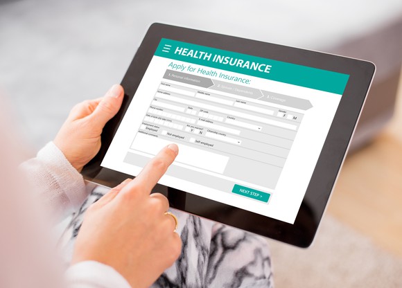 Woman completing health insurance application on tablet.