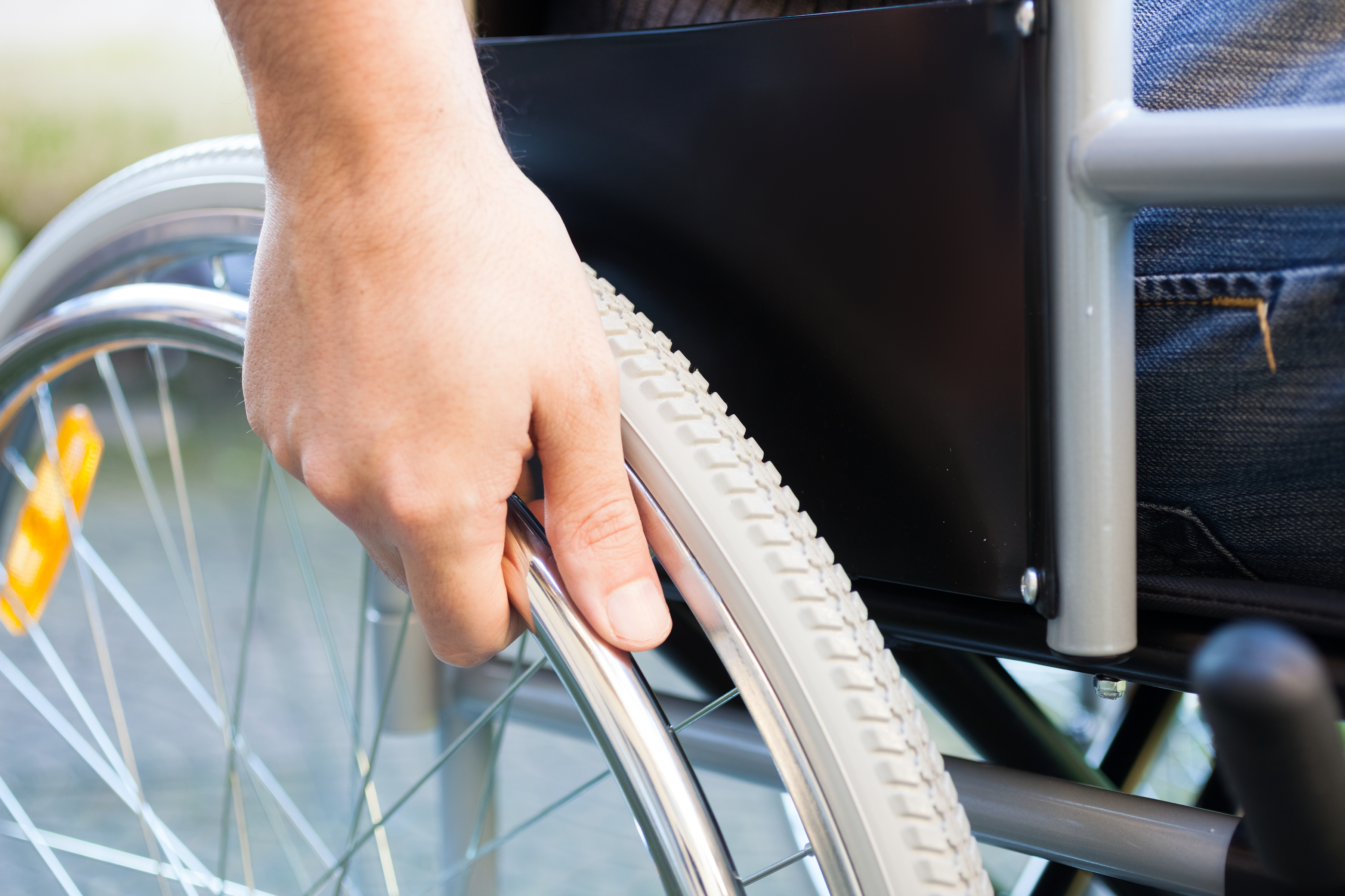 A person in a wheelchair places his hand on the wheel.