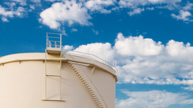 An oil storage tank and blue sky in the background.