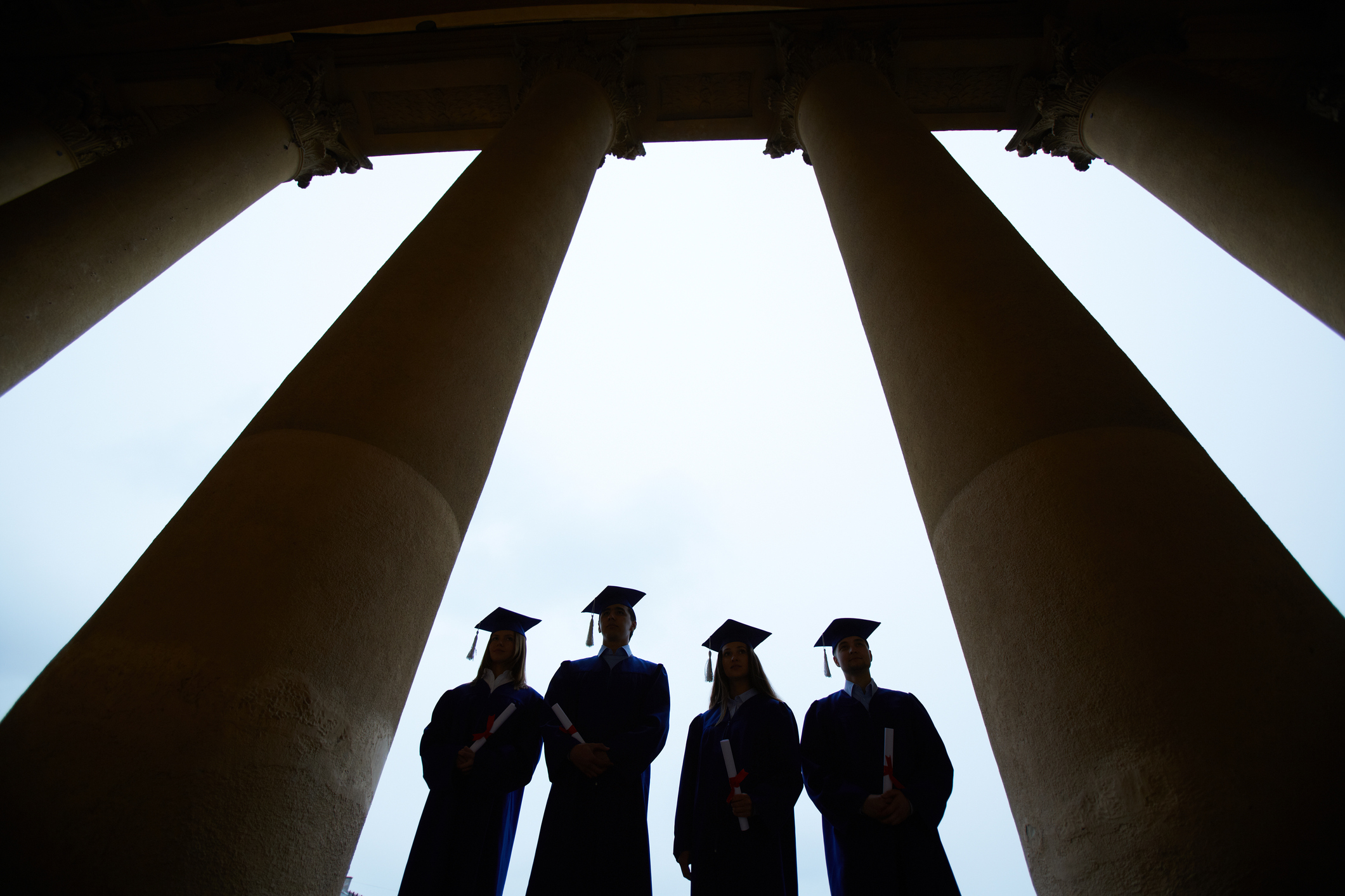 College graduates standing between columns