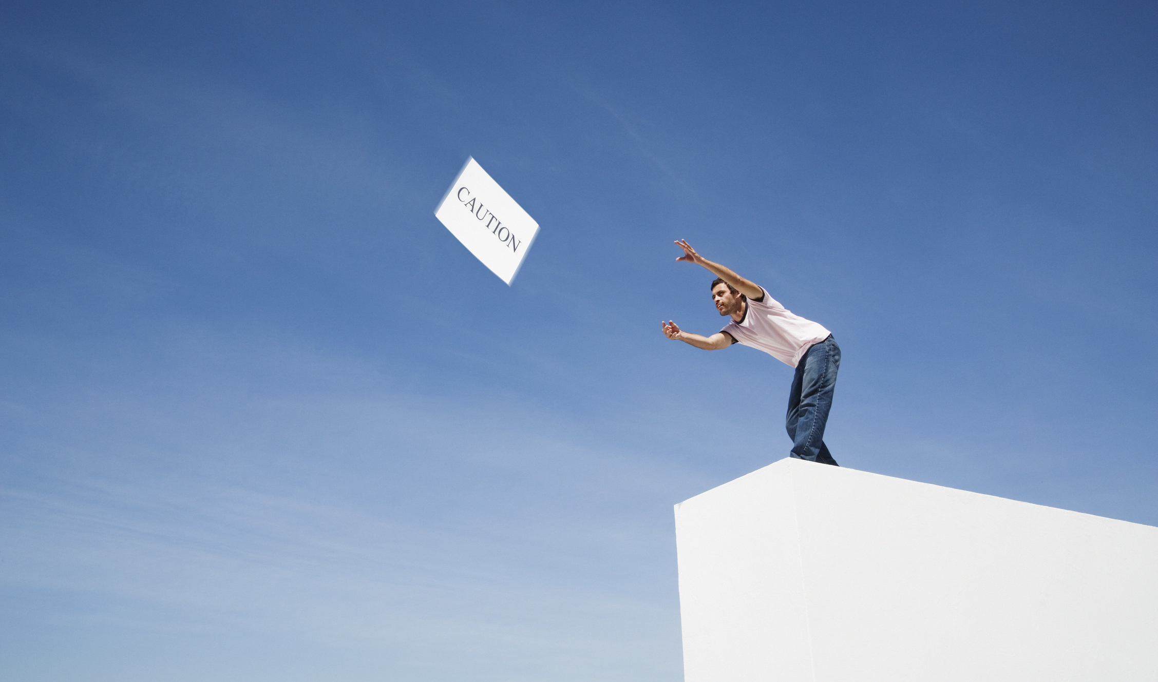 Man throwing a sign with the word "caution" to the wind.