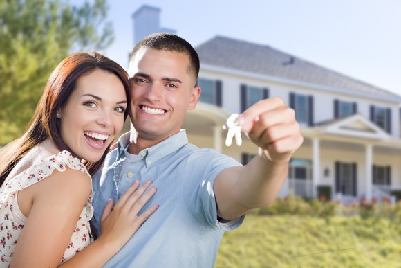Young couple in front of home they just bought.
