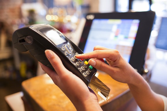 Cashier ringing up a credit card transaction on a handheld credit processing device.