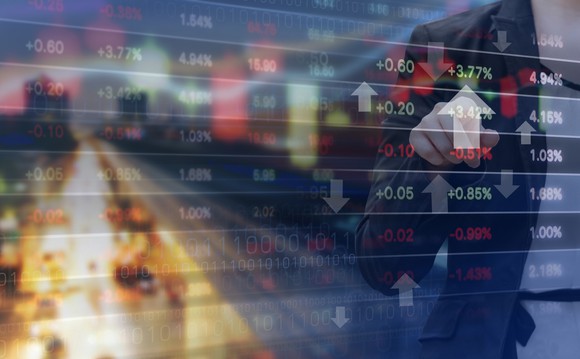 Double exposure of businesswoman and stock market graph with city in the background.