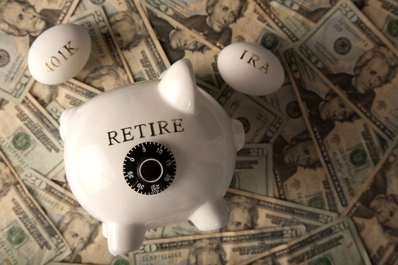 Piggy bank with the word "Retire" on it, sitting on a pile of cash. Also two eggs, one with '401k' written on it and the other with 'IRA' written on it.