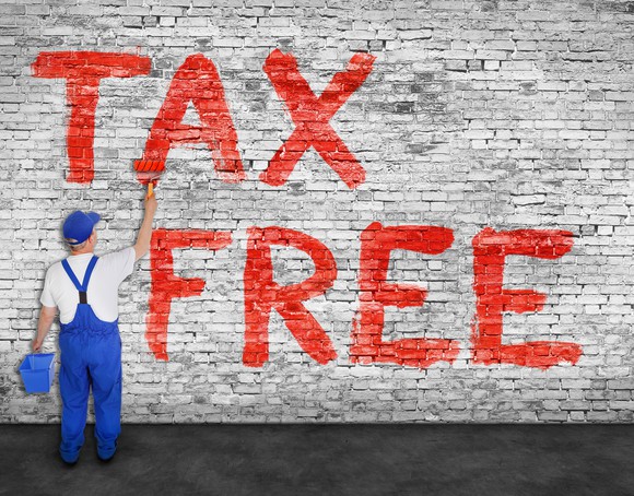 Painter painting tax-free sign in red on a brick wall.
