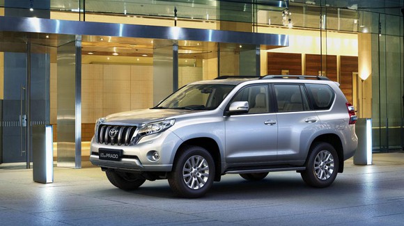 A silver Prado SUV in front of a store.