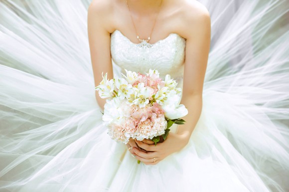 Bride wearing white wedding dress and holding bouquet of flowers.