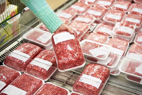 Woman selecting package of ground beef.