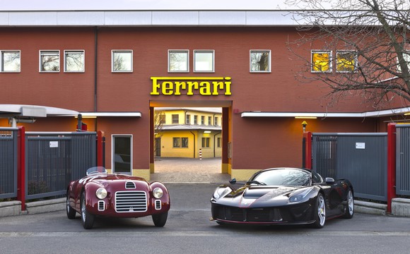 A 1947 Ferrari 125 S and a 2017 LaFerrari Aperta are parked before the historic entrance to Ferrari's headquarters campus in Maranello, Italy.