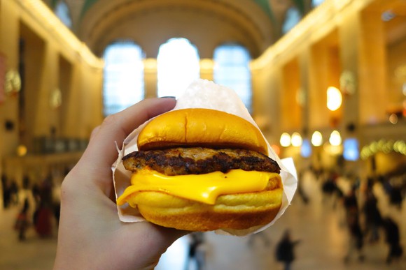 A hand holding aShake Shack cheeseburger.