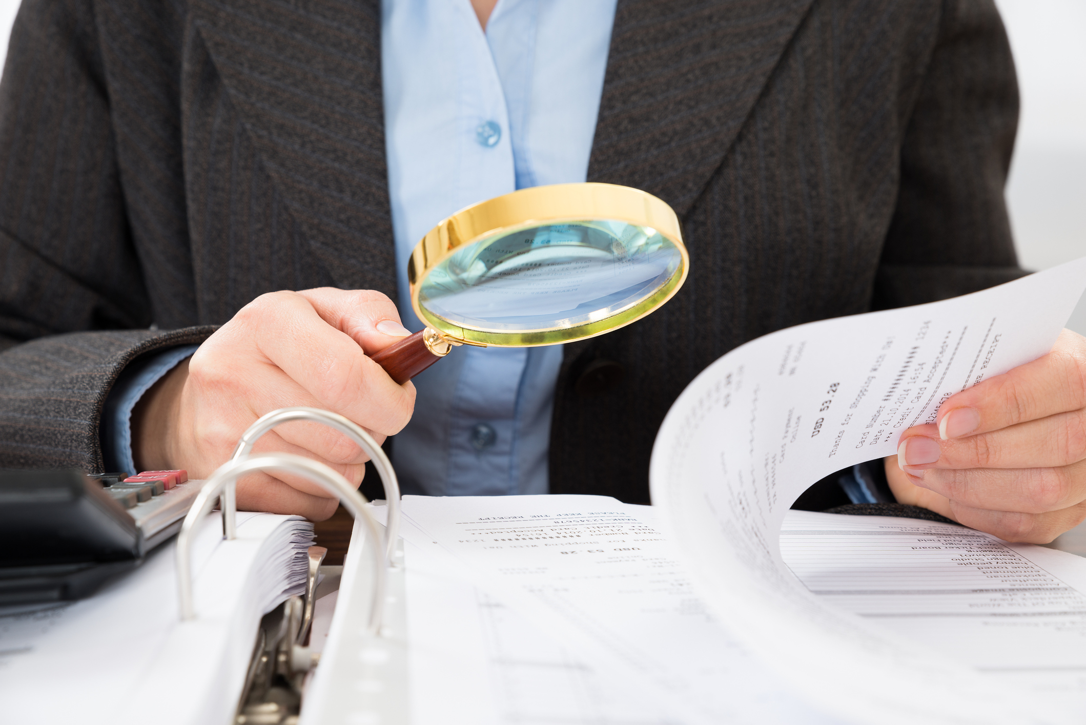 Looking through documents with a magnifying glass.