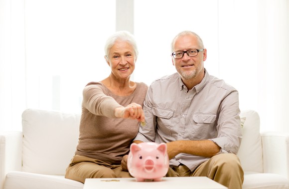 Older couple putting money into a piggy bank