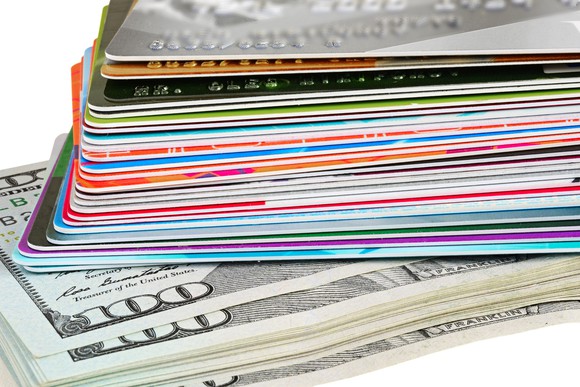 pile of about 20 credit cards sitting on a pile of hundred dollar bills