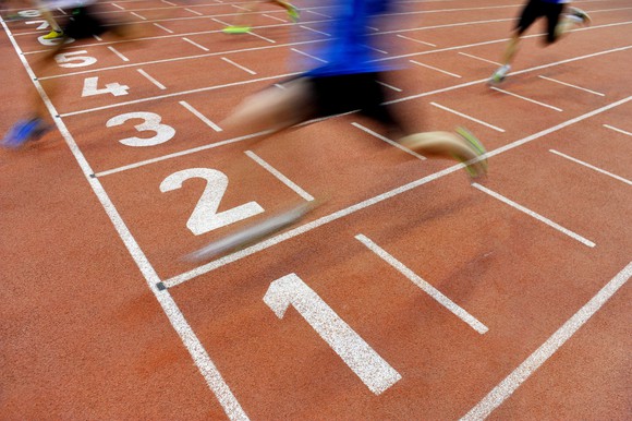 Runners cross a finish line in a blur of motion.