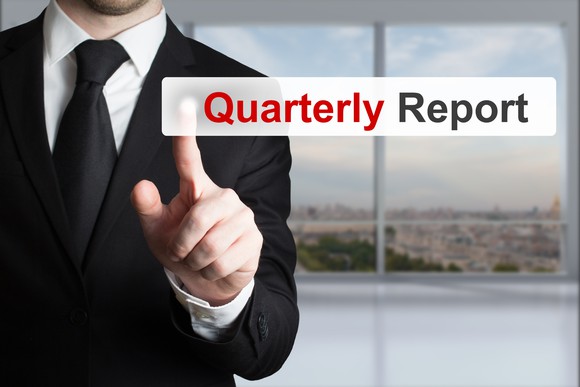 An investor in a suit clicking on the "quarterly report" tab on his digital screen.