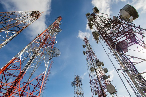 A view looking up at several telecom wireless towers.