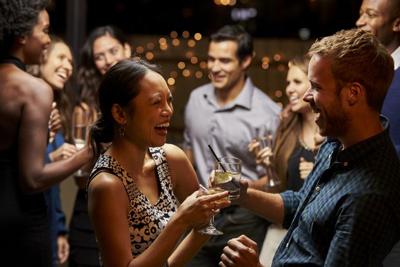 Couples dance and drink at an evening party.