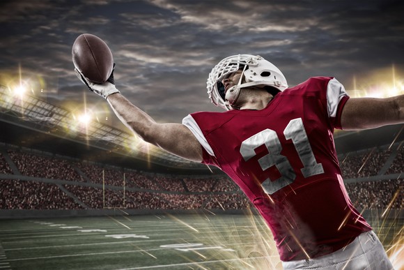 A football player stretches his arm to catch the ball.