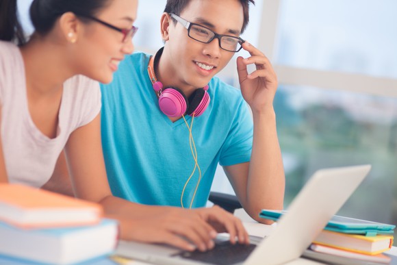 Two students surfing the internet on a laptop.