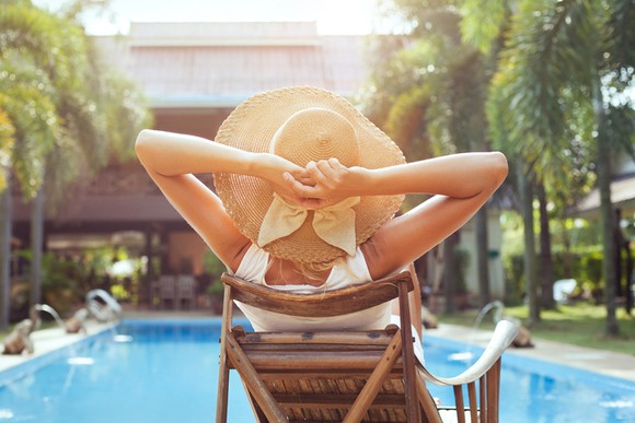 A woman relaxes by a luxury hotel poolside in the summer.