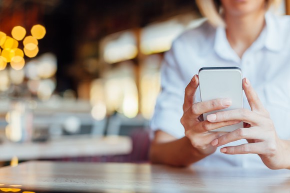 A woman holds a mobile phone in a cafe.