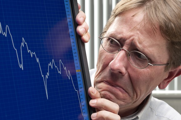 A man looking at a plunging stock chart.