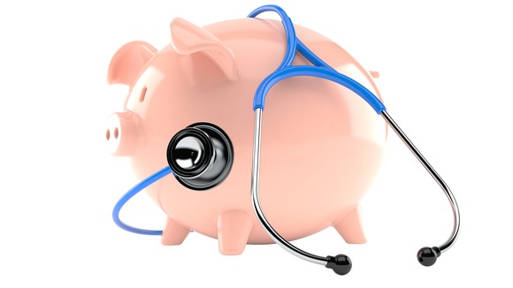 A stethoscope is wrapped around a piggy bank.