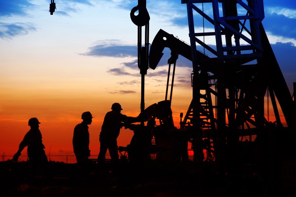 Oil workers on a rig at sunset.