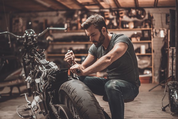 A man works on a motorcyle in a garage. 