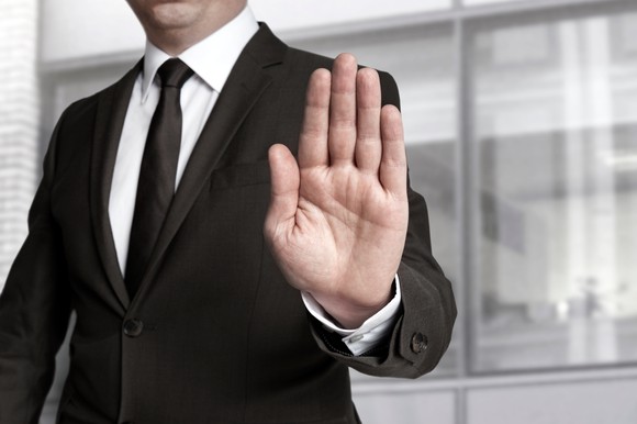 A businessman holds up his hand to signal a stop.