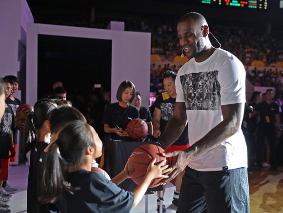 LeBron James hands a young fan a basketball.