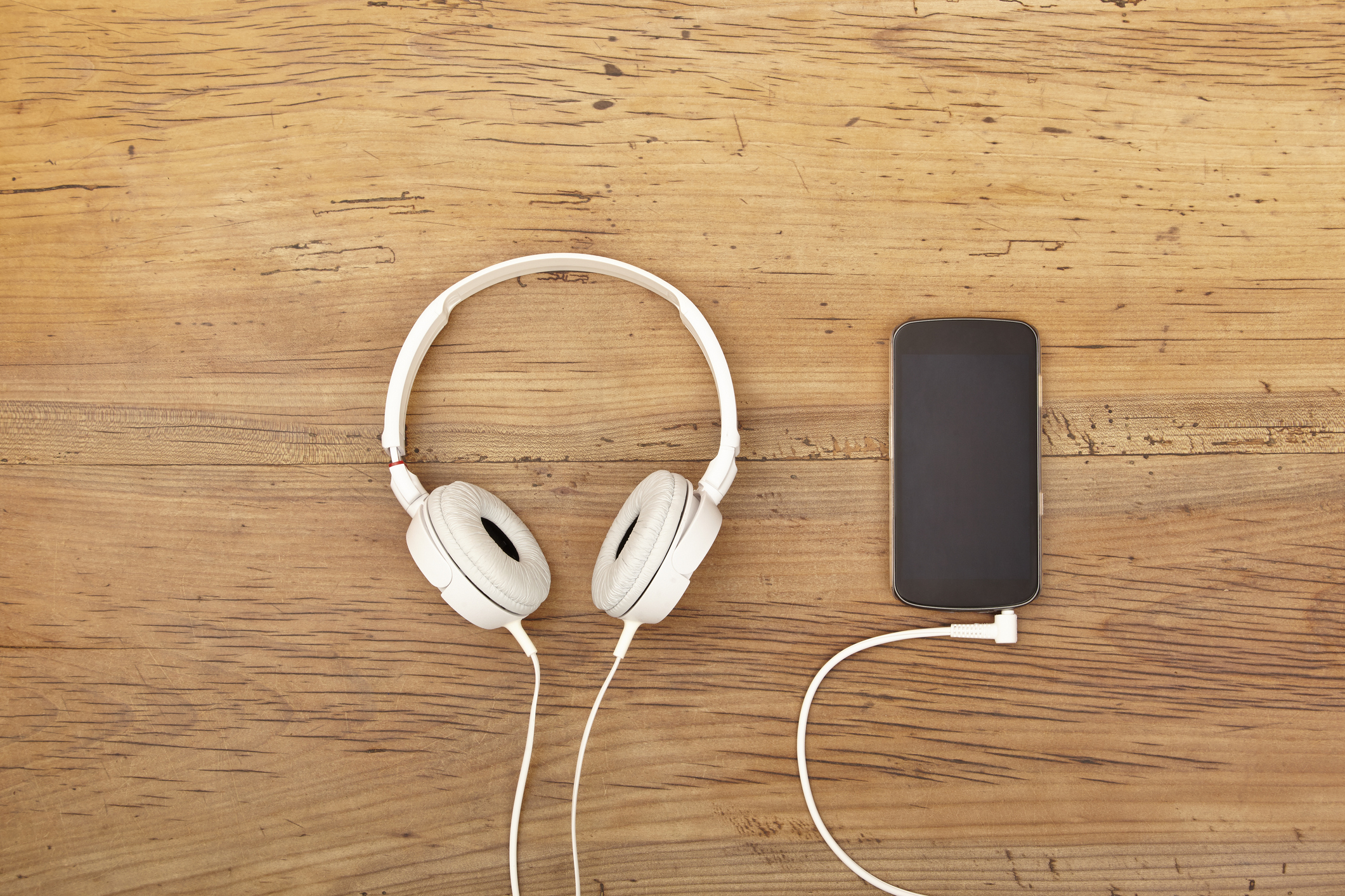 White headphones sitting next to a smartphone.