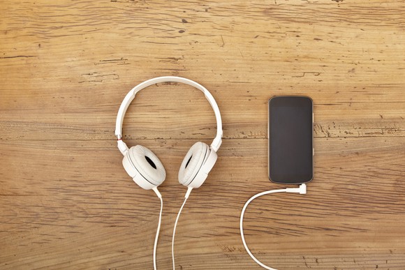 White headphones sitting next to a smartphone.