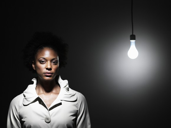 Woman standing near a light bare lightbulb.