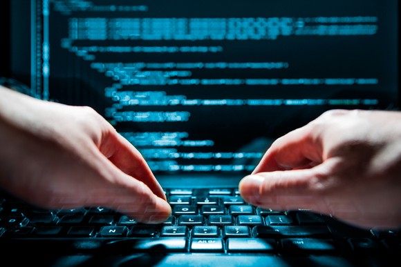 Hands on a computer keyboard in a dimly lit room